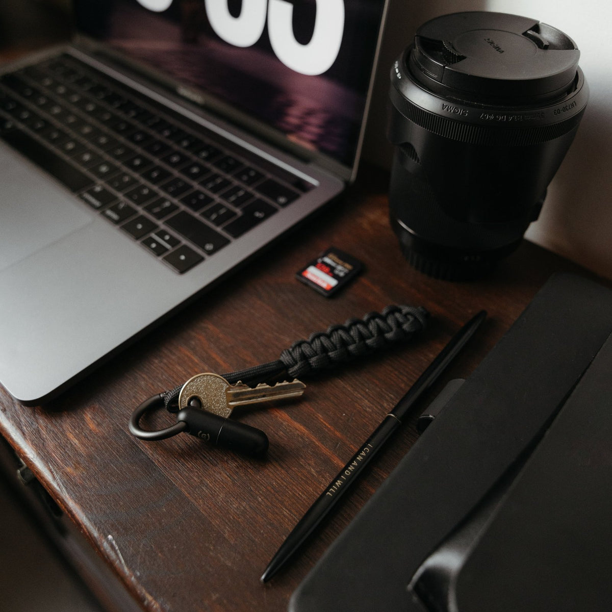 Everyday carry on a wooden desk: keys on a paracord lanyard with a black Microblade Pill